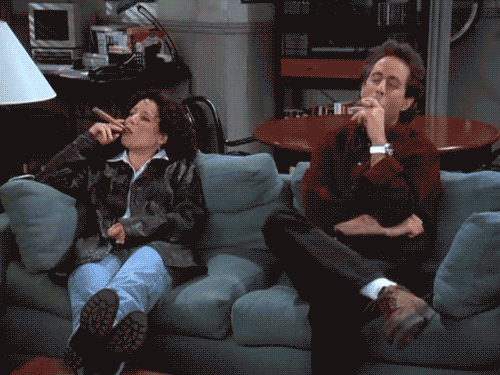 Elaine-Benes-and-Jerry-Seinfeld-Sitting-on-Couch-Smoking-Cigars.gif
